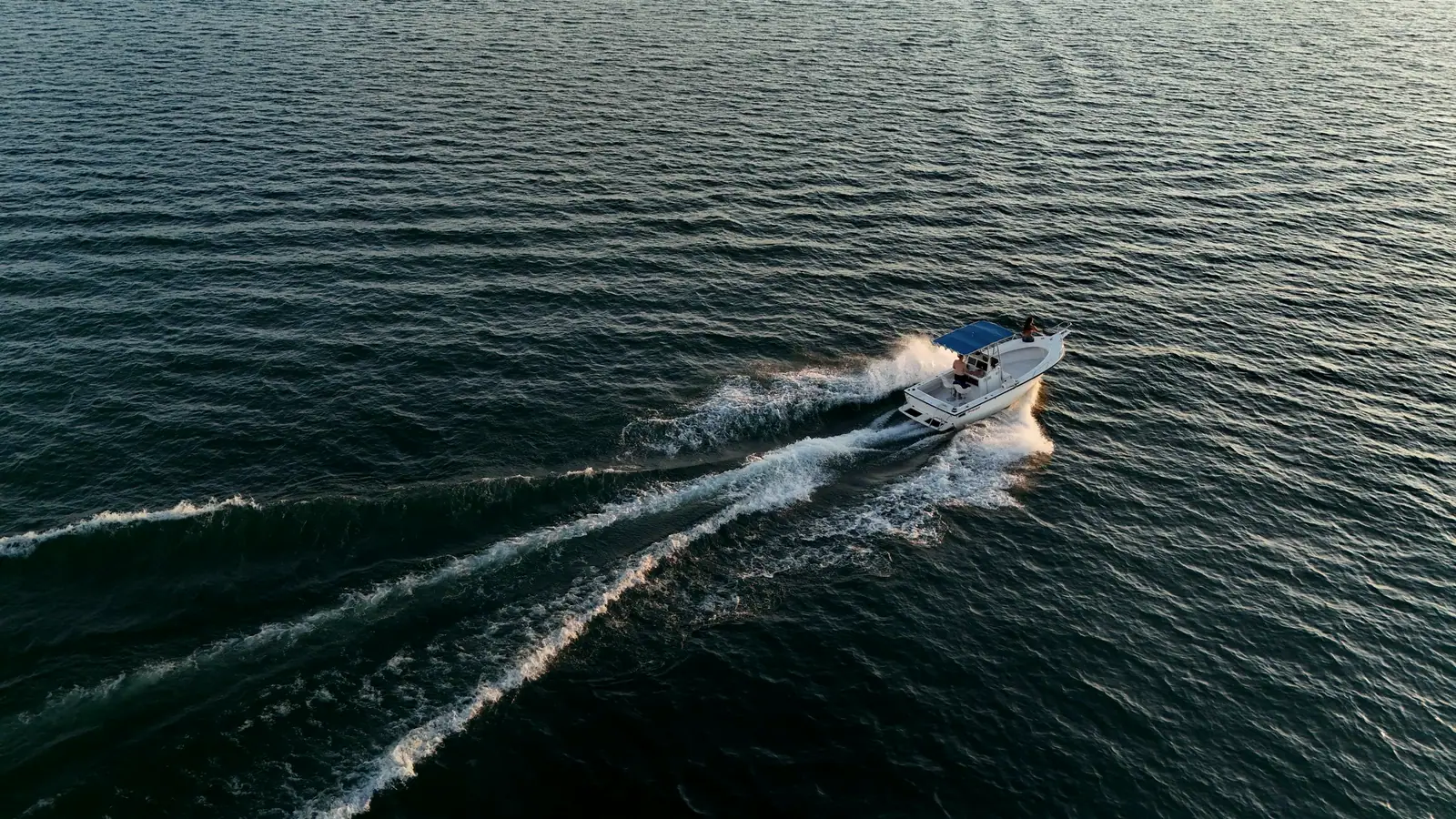 Un bateau trace son sillage sur l'eau sombre